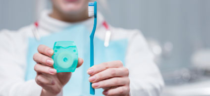 Hombre mostrando cepillo y seda dental